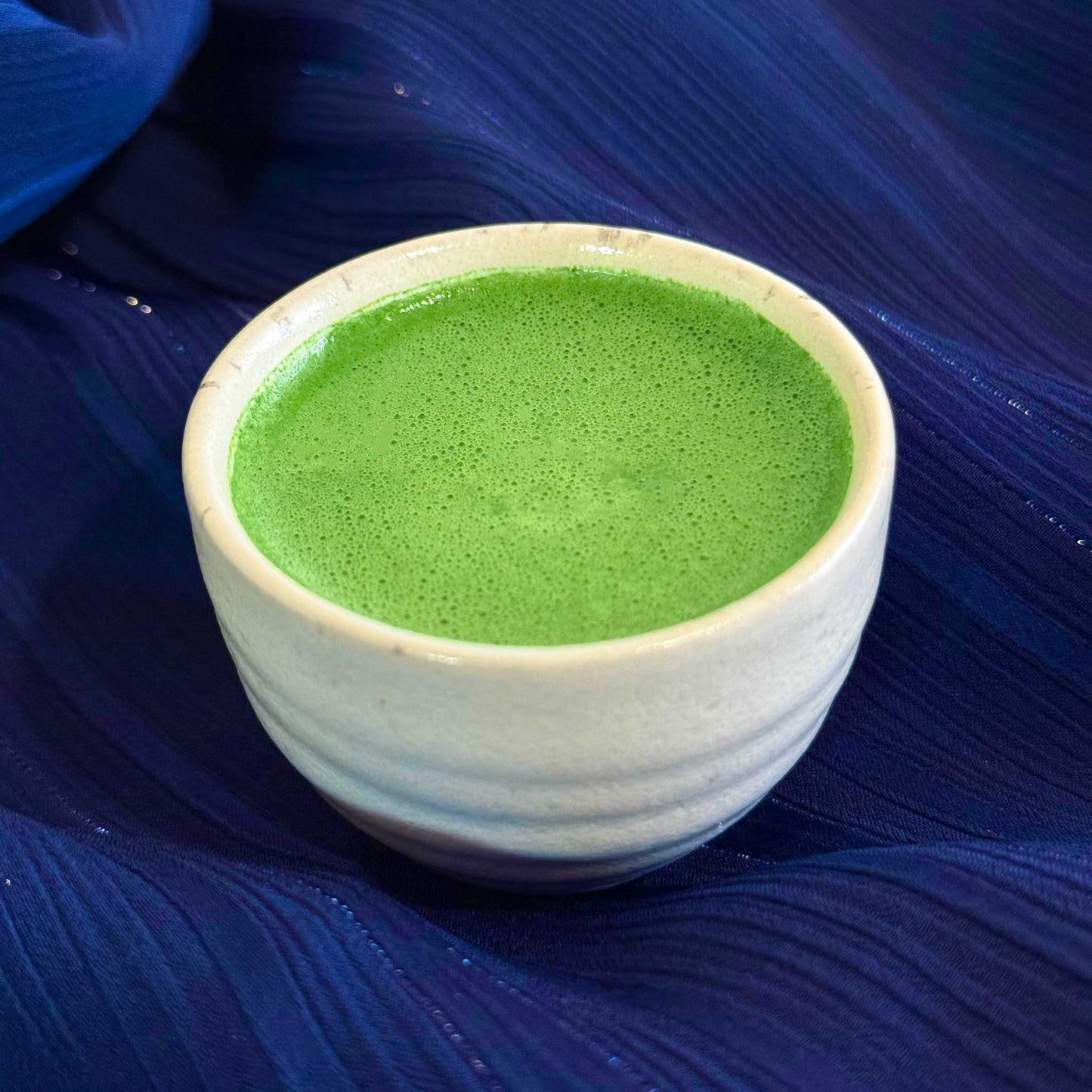 Nishi no Kawa Matcha prepared as usucha in a white cup on a blue background