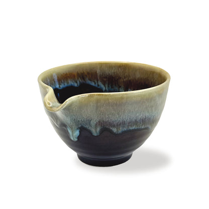 Brown matcha ceramic bowl with green and blue dripping glaze on a white background