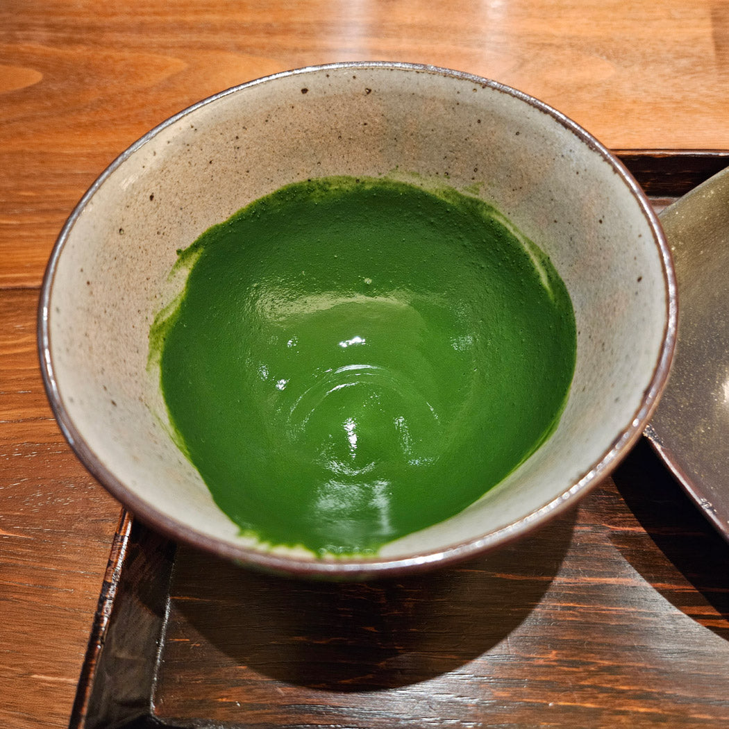 Koicha matcha prepared in a grey ceramic bowl on  a wooden tray