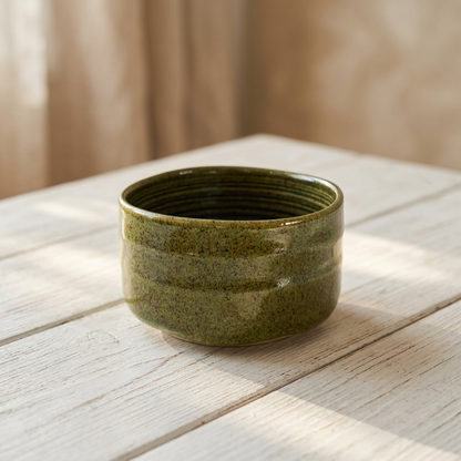 Green ceramic bowl on a wooden surface with a blurred background